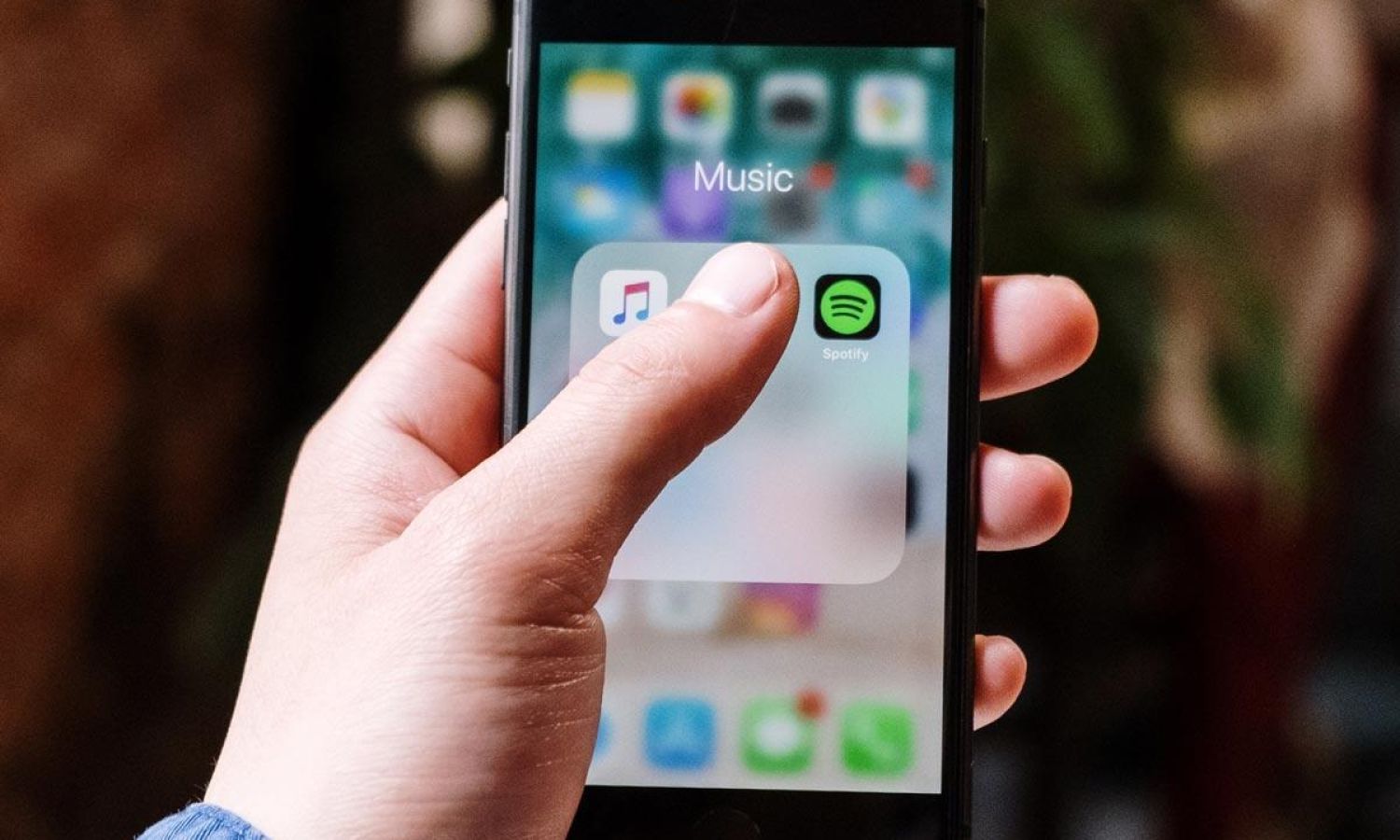Man's hand touching an iPhone app to open